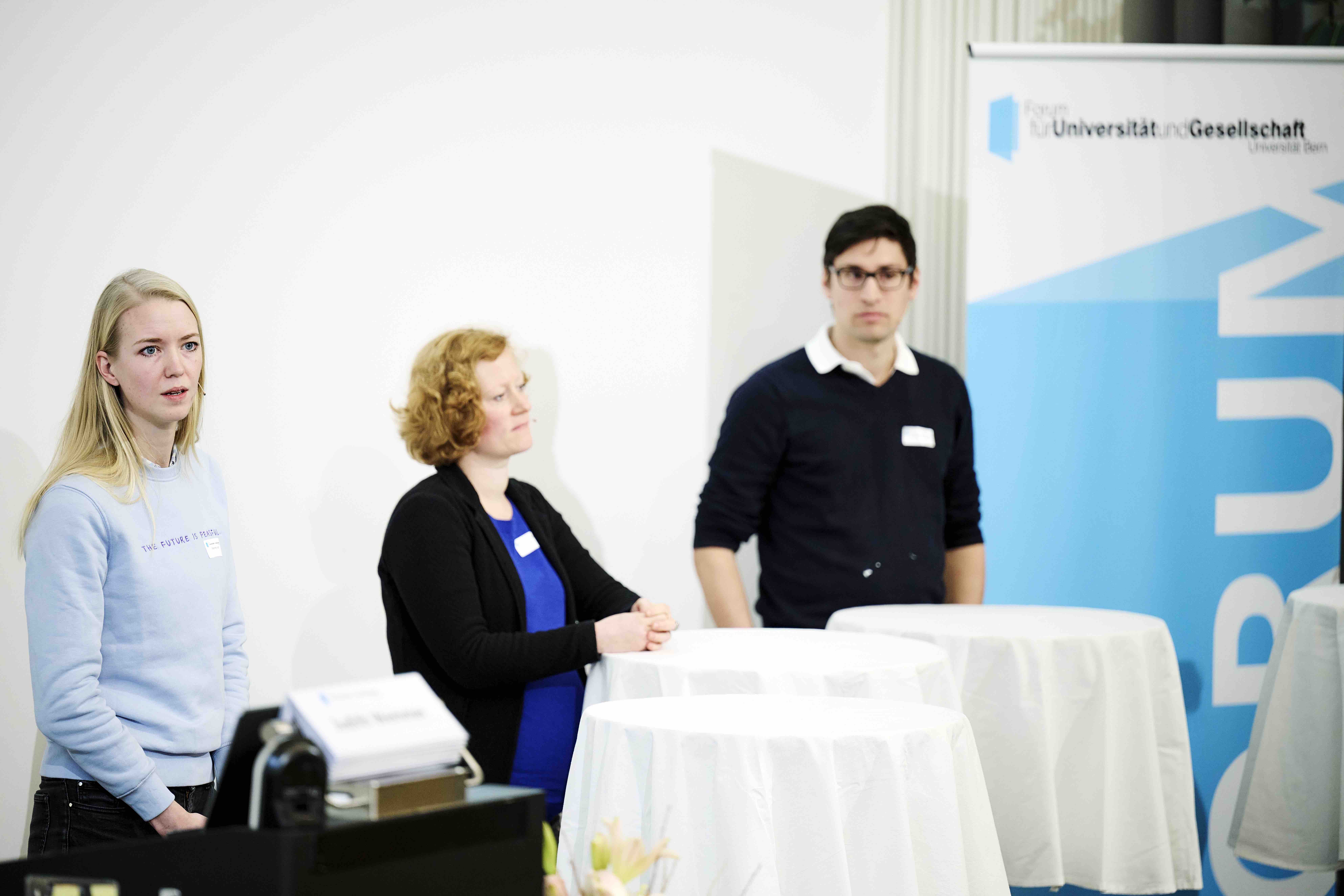 Judith Wemmer, Karin Spori und Christian Bärtsch stehen während ihrer Podiumsdiskussion an Stehtischen mit weissen Tischtüchern. Im Hintergrund ist ein Banner mit dem blauweissen Forumslogo sichtbar.