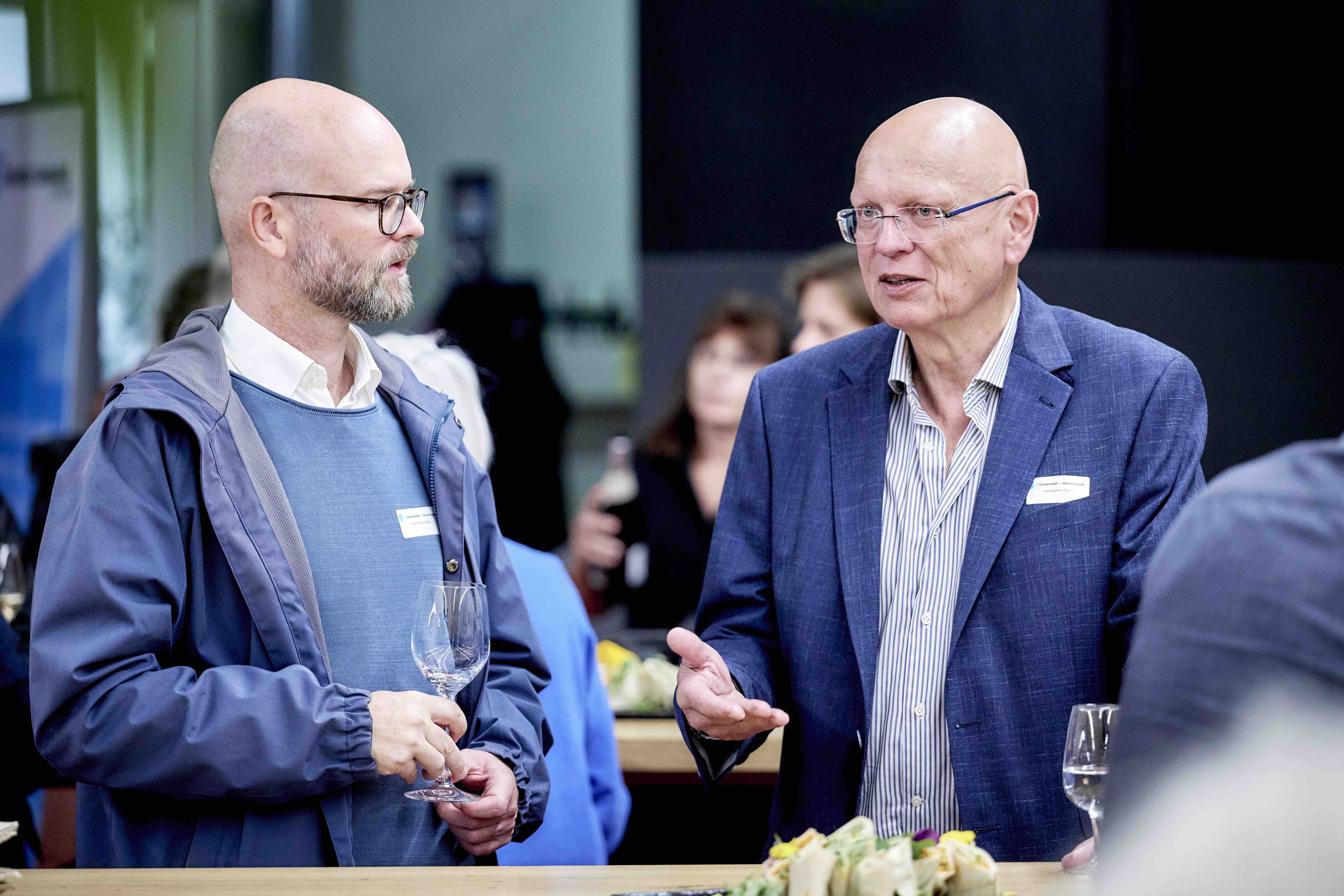 Forumspräsident Heinzpeter Znoj (rechts) im Gespräch mit dem Referent Hendrik Budliger. Beide Herren tragen blaue Kleidung und Brille.