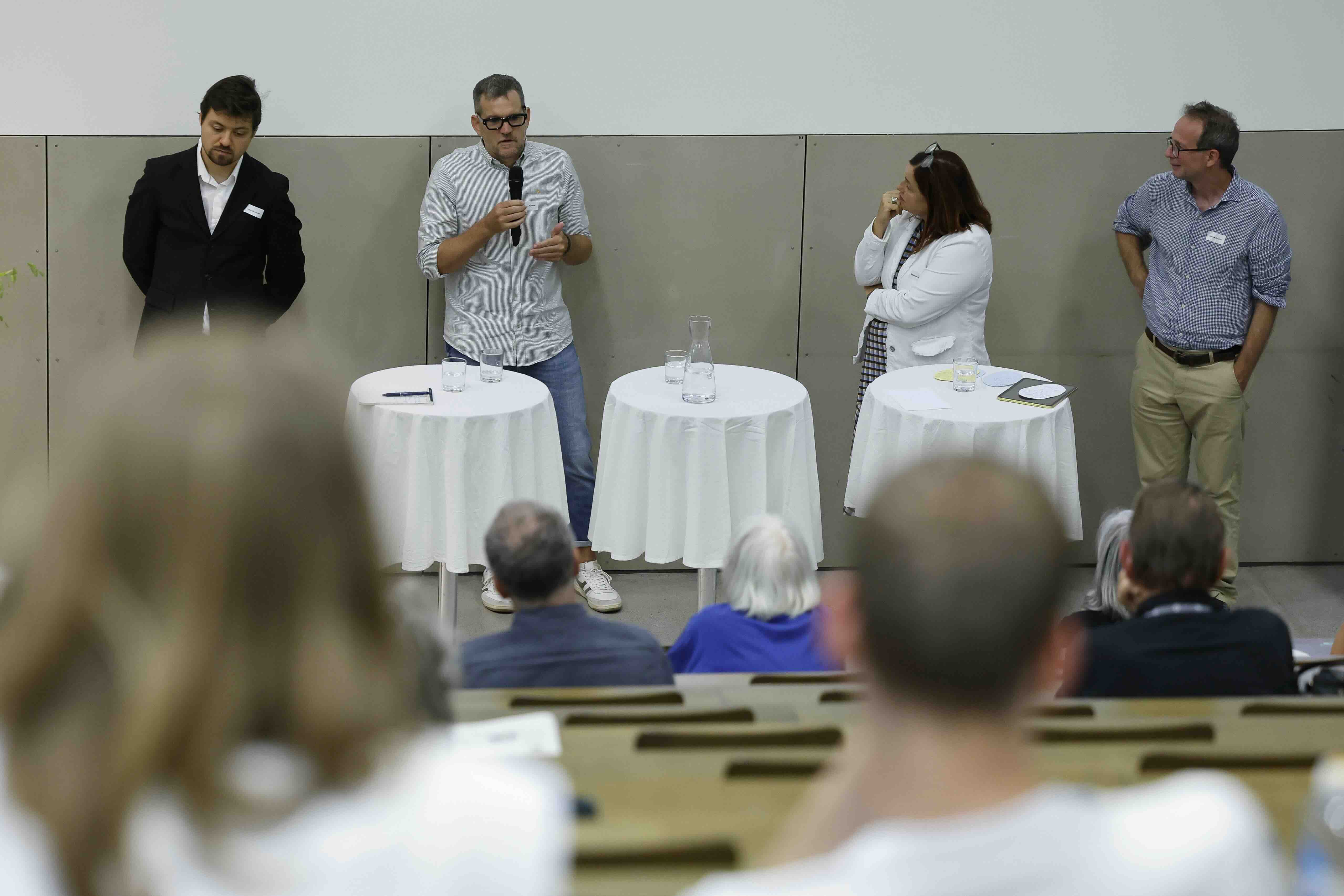 Julian Marciniak, Thomas Heldner, Madeleine Zbinden und Dominik Scherrer stehen hinter drei Stehtischen an der Podiumsdiskussion zum Thema «Die Arbeitswelt im Wandel»