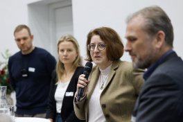 Vier Personen stehen nebeneinander. Die zweite von rechts spricht in ein Handmikrofon.